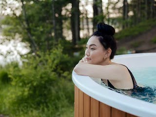 Frau entspannt in Außen-Whirlpool im grünen