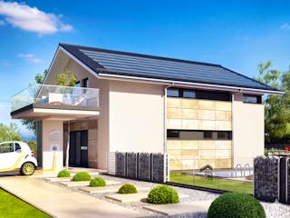 Musterhaus CONCEPT-M 163 München von Bien-Zenker mit Photovoltaikanlage auf dem Satteldach und Wallbox am Eingang, an der ein kleines Elektroauto mit gelbem Ladekabel lädt.
