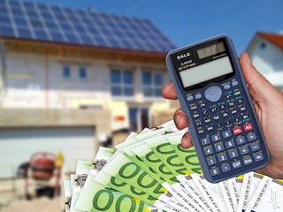 Taschenrechner und Geldscheine vor Hausbaustelle
