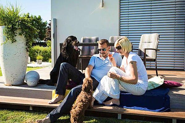 Mann und Frau mit 2 Hunden auf der Terrasse